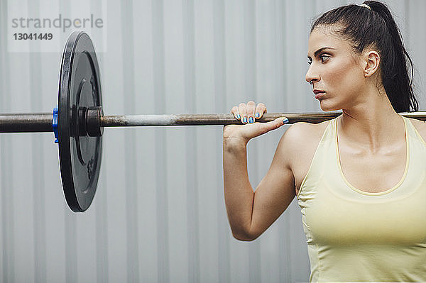 Athlet schaut beim Gewichtheben mit Langhantel im Fitnessstudio weg