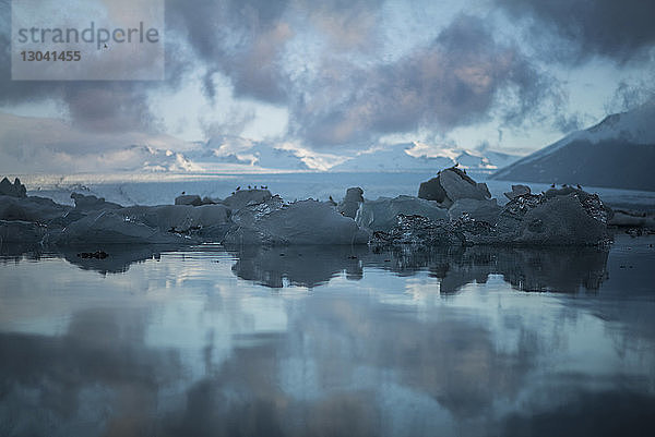 Szenische Ansicht eines Gletschers im Meer vor bewölktem Himmel