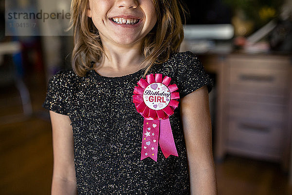 Mitschnitt eines glücklichen Mädchens mit Geburtstagsabzeichen zu Hause