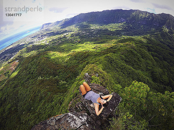 Hochwinkelaufnahme einer Frau  die sich auf einem Bergfelsen entspannt