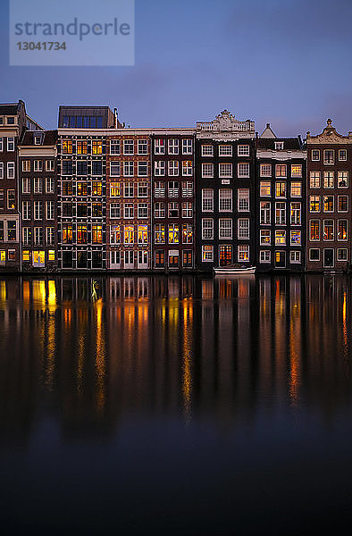 Gebäude reflektieren auf ruhigem Kanal gegen blauen Himmel in der Dämmerung