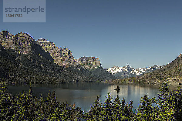 Panoramablick auf den See inmitten der Berge bei strahlend blauem Himmel im Glacier National Park