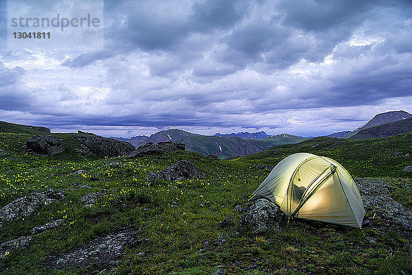 Beleuchtetes Zelt auf dem Feld gegen Gewitterwolken im San Juan National Forest
