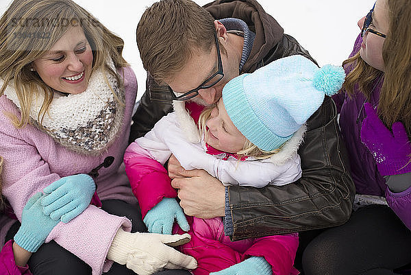 Nahaufnahme einer glücklichen Familie  die im Winter auf dem Feld sitzt