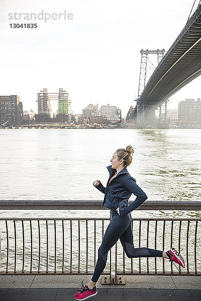 Seitenansicht eines Athleten  der auf der Promenade am East River läuft