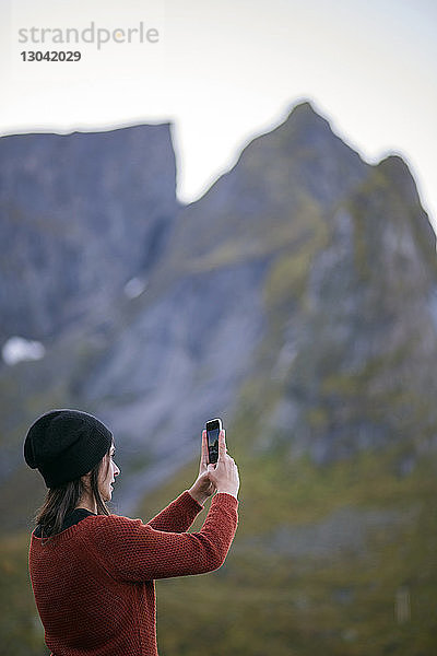Seitenansicht einer Frau  die per Mobiltelefon Berge fotografiert