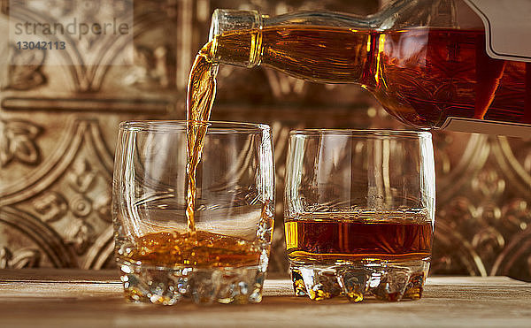 Nahaufnahme des Whiskeys  der auf dem Tisch in ein Glas gegossen wird