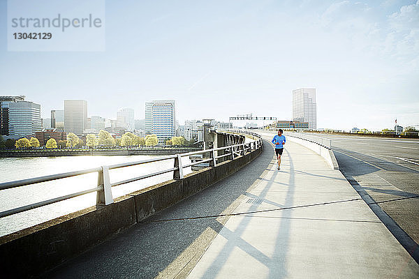 Athlet schaut weg  während er in der Stadt auf einer Brücke läuft