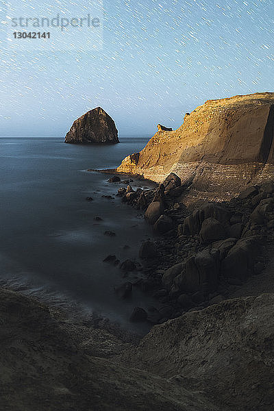 Hochwinkel-Szenenansicht einer Felsformation im Meer gegen ein Sternenfeld