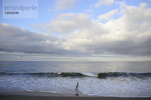 Mädchen spielt im Meer am Laguna Beach gegen bewölkten Himmel