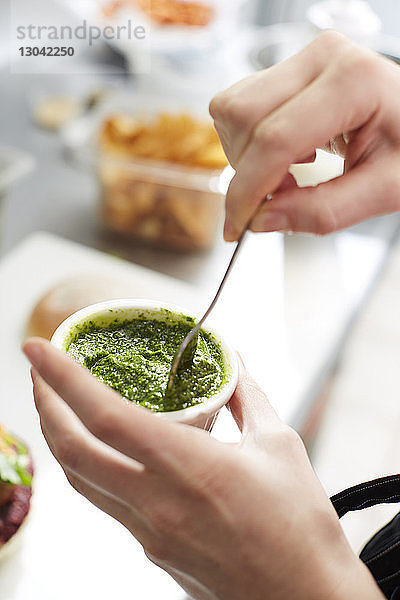 Abgehackte Hände einer Frau  die in der Küche Pesto macht