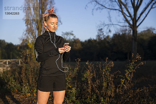 Frau benutzt Smartphone beim Sport im Park