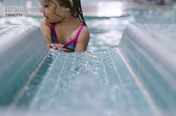 Mädchen steht gegen Wasserrutsche im Schwimmbad