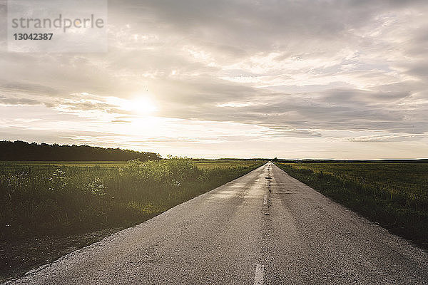 Landstraße mitten im Feld gegen bewölkten Himmel