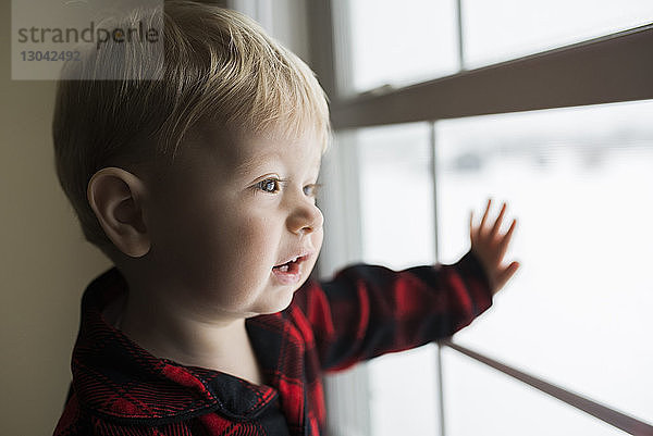 Süßer Junge schaut zu Hause durchs Fenster