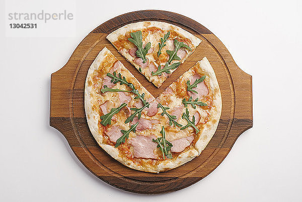 Draufsicht auf Pizza auf Servierbrett über weißem Hintergrund