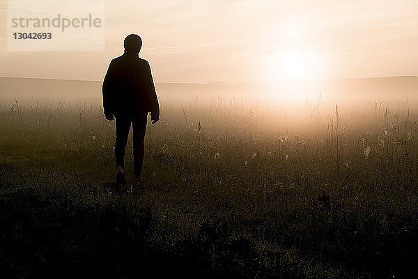 Silhouettenmann steht bei Sonnenuntergang auf dem Feld