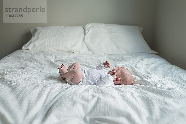 Seitenansicht eines Neugeborenen  der weint  während er zu Hause im Bett liegt