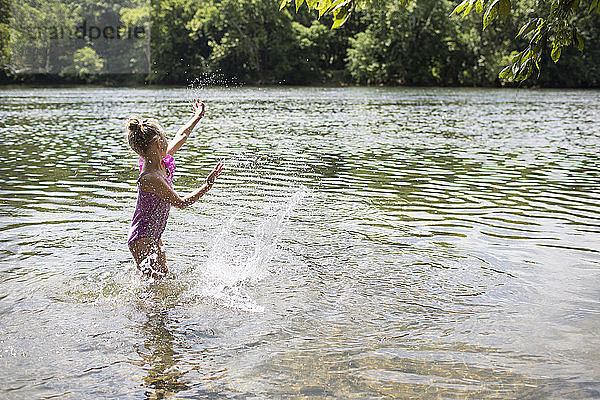 Seitenansicht eines Mädchens  das im See stehend Wasser spritzt