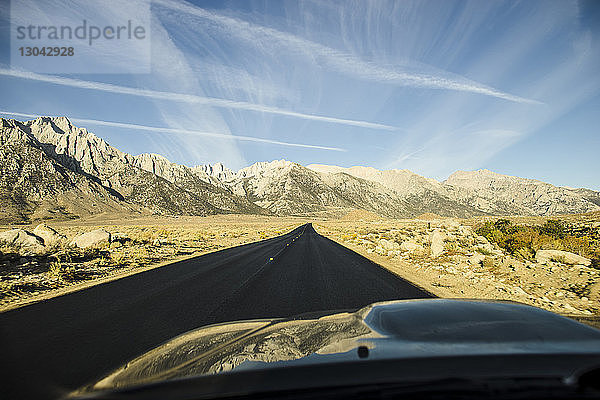 Landstraße  die zum Berg führt  gegen den Himmel durch die Windschutzscheibe des Autos gesehen