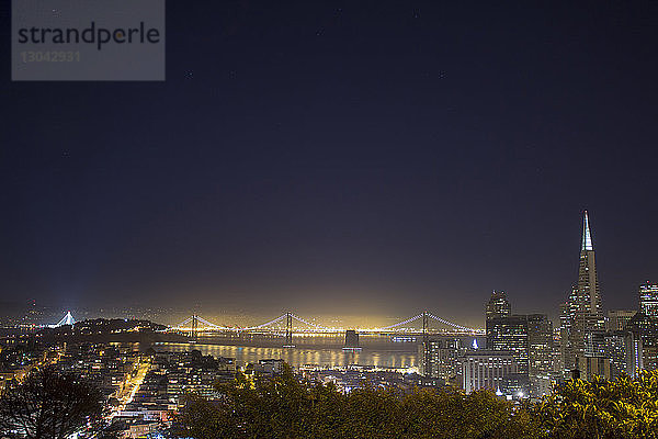 Hochwinkelansicht der beleuchteten Brücke durch die Stadt gegen den klaren Himmel bei Nacht