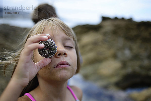 Mädchen spielt mit Seeigel am Laguna Beach