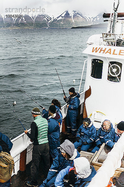Hochwinkelaufnahme von Menschen  die während der Fahrt im Boot auf See fischen