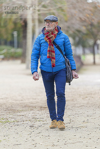 Mann in warmer Kleidung schaut beim Spaziergang auf dem Feld im Park weg