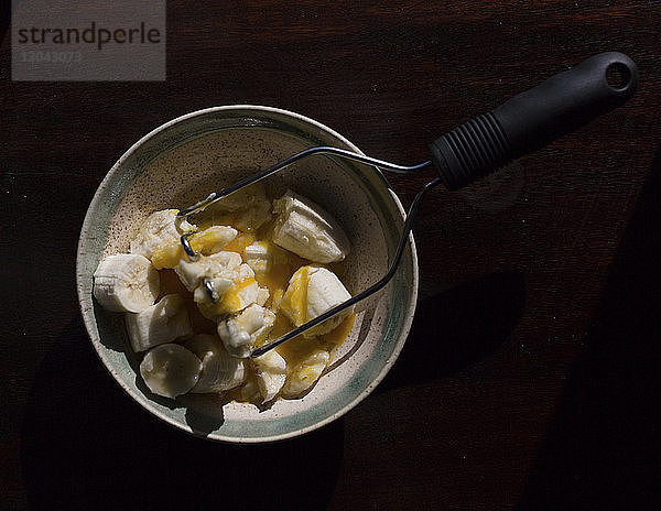 Draufsicht auf Bananenscheiben und Eier in Schale mit Stampfer auf dem Tisch