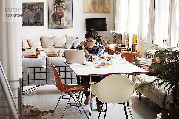 Mann mit Laptop am Tisch im Haus