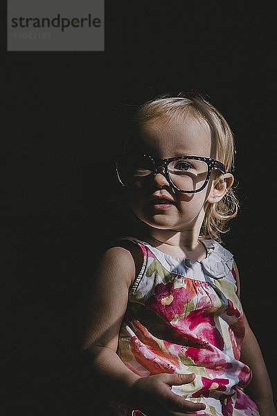 Porträt eines süßen Mädchens mit Brille in der Dunkelkammer