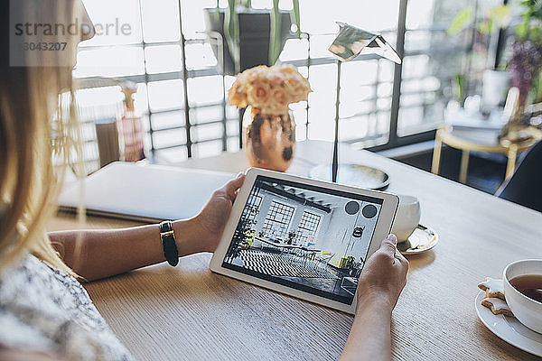 Ausgeschnittenes Bild einer Geschäftsfrau  die einen Tablet-Computer hält  während sie am Tisch sitzt