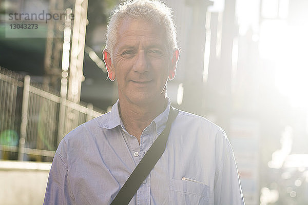 Porträt eines lächelnden Mannes  der an einem sonnigen Tag in der Stadt steht
