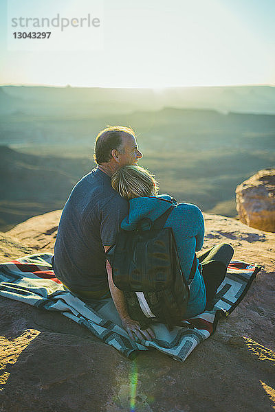 Rückansicht eines romantischen Paares  das auf einem Berg im Canyonlands-Nationalpark sitzt