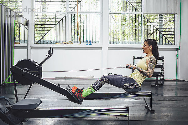 Sportler mit Rudergerät im Fitnessstudio