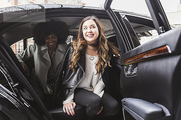 Fröhliche Geschäftsfrauen beim Aussteigen aus dem Auto