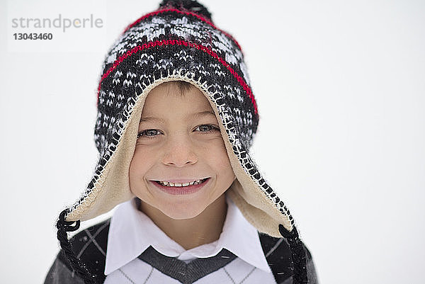 Nahaufnahme eines lächelnden Jungen mit Strickmütze im Winter