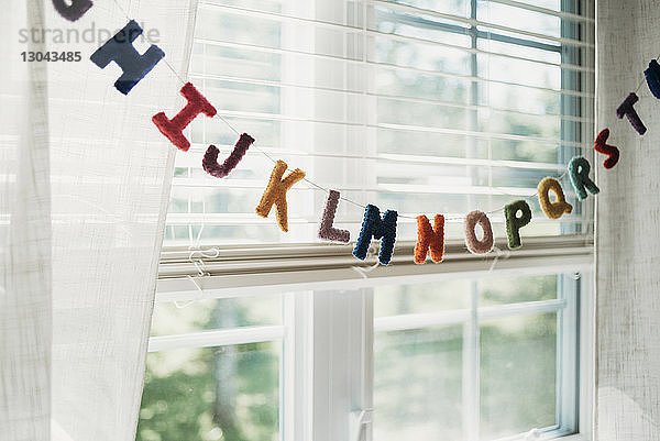 Mehrfarbige Alphabetdekoration  die zu Hause am Fenster an einer Schnur hängt