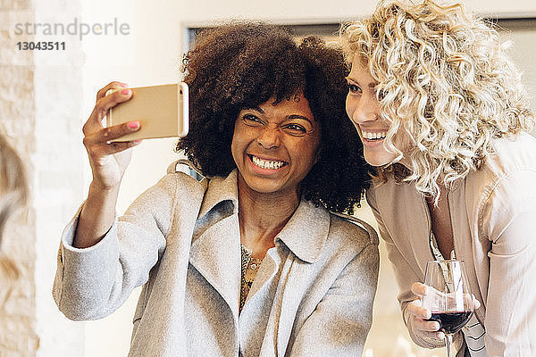 Fröhliche Geschäftsfrauen  die sich im Hotel mit einem Smartphone selbstständig machen