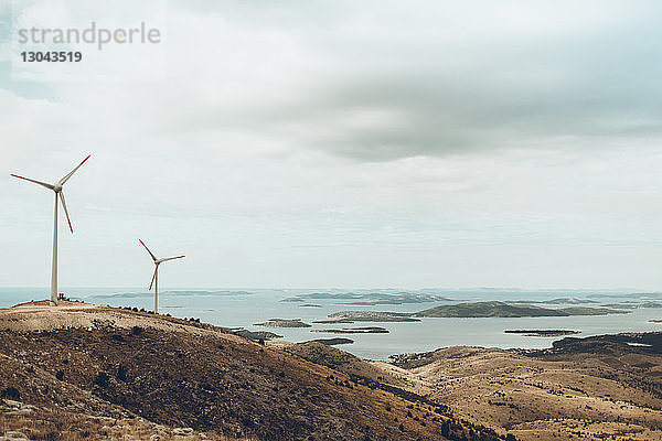 Windmühlen auf einem Hügel am Meer gegen bewölkten Himmel