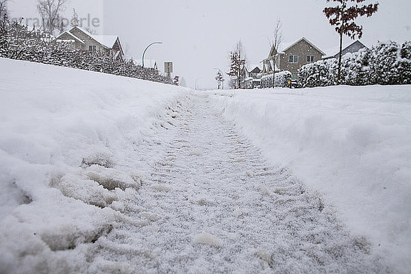 Ebenflächige Aufnahme der Reifenspur auf schneebedeckter Straße in der Stadt