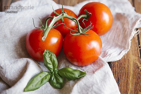 Nahaufnahme von Tomaten und Basilikum auf Textil bei Tisch