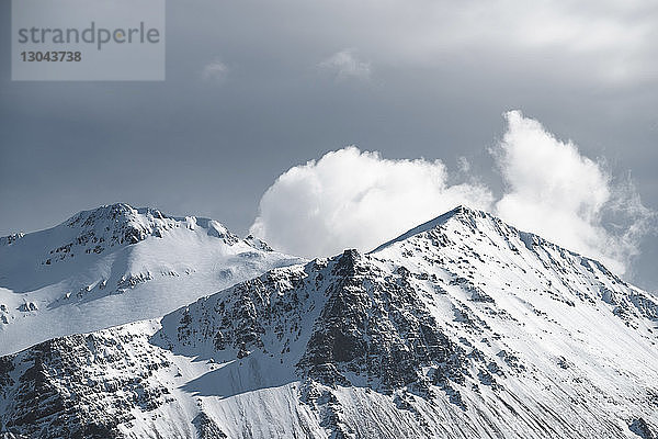 Landschaftliche Ansicht von schneebedeckten Bergen vor bewölktem Himmel