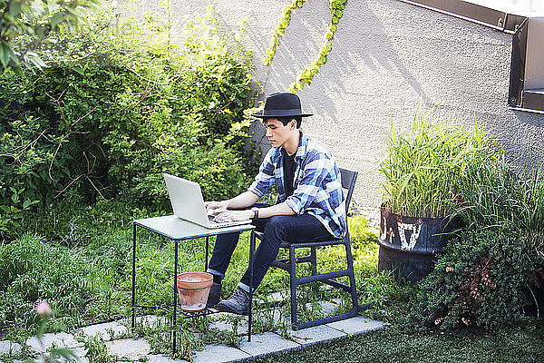 Mann mit Laptop auf der Terrasse
