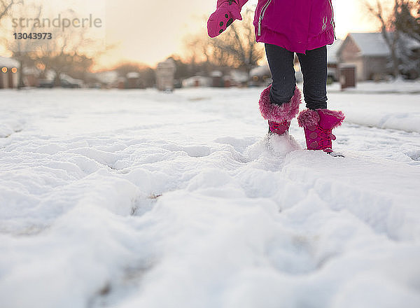 Niedriger Teil eines Mädchens spielt mit Schnee auf dem Feld