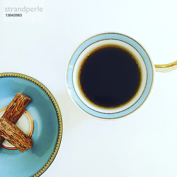 Draufsicht auf Kaffeetasse und Snacks auf weißem Tisch