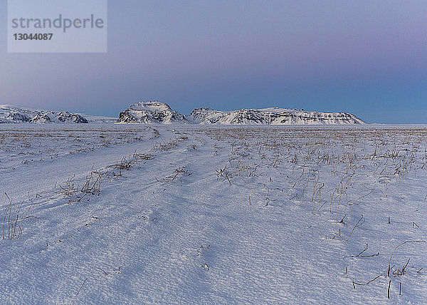 Szenische Ansicht eines schneebedeckten Feldes gegen Berge und Himmel