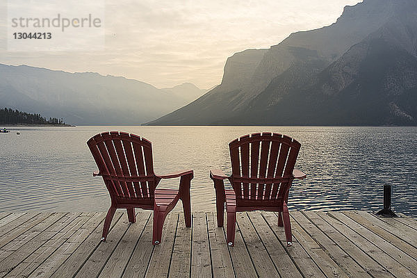 Stühle auf dem Steg über dem Minnewanka-See gegen die Berge im Banff-Nationalpark