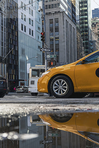 Taxi reflektiert über Pfütze in der Stadt während der Regenzeit