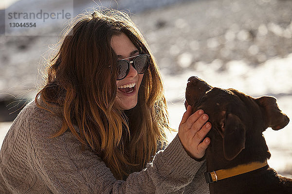 Glückliche Frau streichelt Hund im Winter